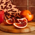 sliced orange fruit on brown wooden chopping board